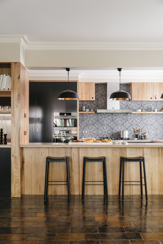 This is an example of a large modern u-shaped open plan kitchen in Adelaide with flat-panel cabinets, medium wood cabinets, solid surface benchtops, grey splashback, ceramic splashback, stainless steel appliances, slate floors, with island and multi-coloured floor.