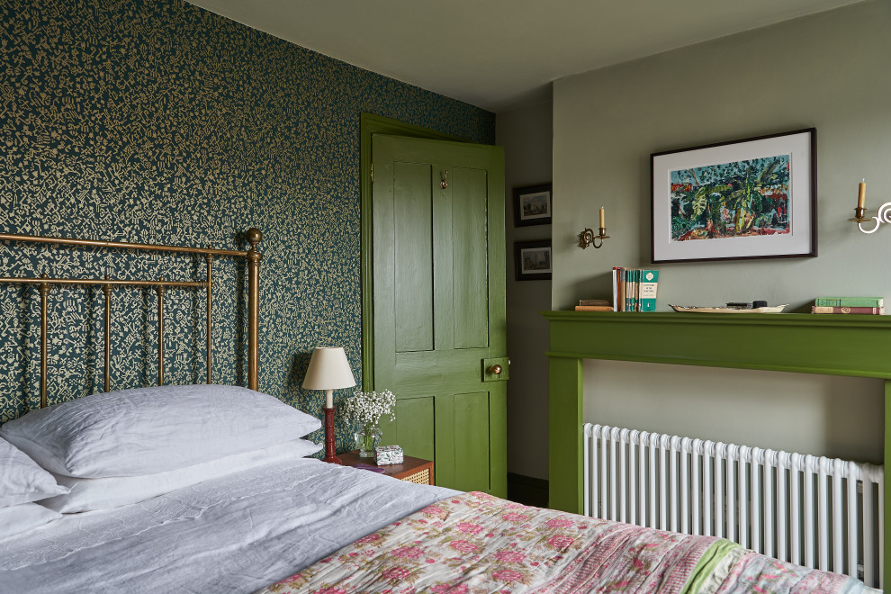 Réalisation d'une grande chambre tradition avec un mur vert, un manteau de cheminée en bois et du papier peint.