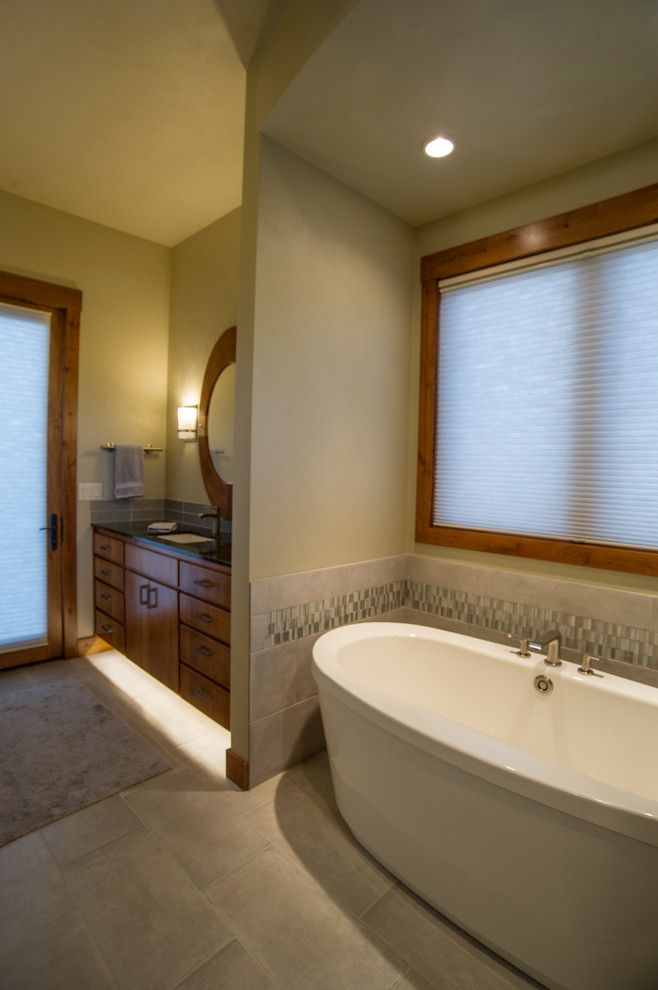 Mid-sized transitional master bathroom in Other with an undermount sink, recessed-panel cabinets, medium wood cabinets, granite benchtops, a freestanding tub, a corner shower, gray tile, cement tile, green walls and porcelain floors.