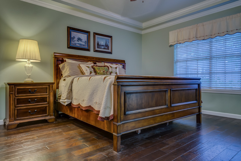 Photo of a large traditional master bedroom in Austin with green walls and dark hardwood floors.