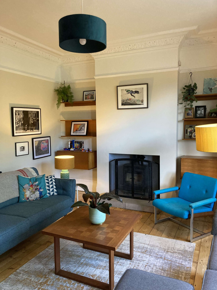 Foto di un grande soggiorno moderno chiuso con pareti beige, parquet chiaro, stufa a legna, cornice del camino in intonaco, TV autoportante e pavimento marrone