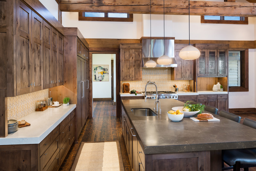 Design ideas for a large country l-shaped eat-in kitchen in Other with an undermount sink, shaker cabinets, brown cabinets, limestone benchtops, yellow splashback, terra-cotta splashback, stainless steel appliances, dark hardwood floors, with island and brown floor.