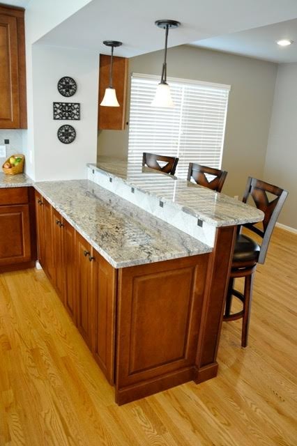 Photo of a mid-sized traditional u-shaped eat-in kitchen in Cincinnati with an undermount sink, recessed-panel cabinets, medium wood cabinets, granite benchtops, grey splashback, stone tile splashback, stainless steel appliances, medium hardwood floors and with island.