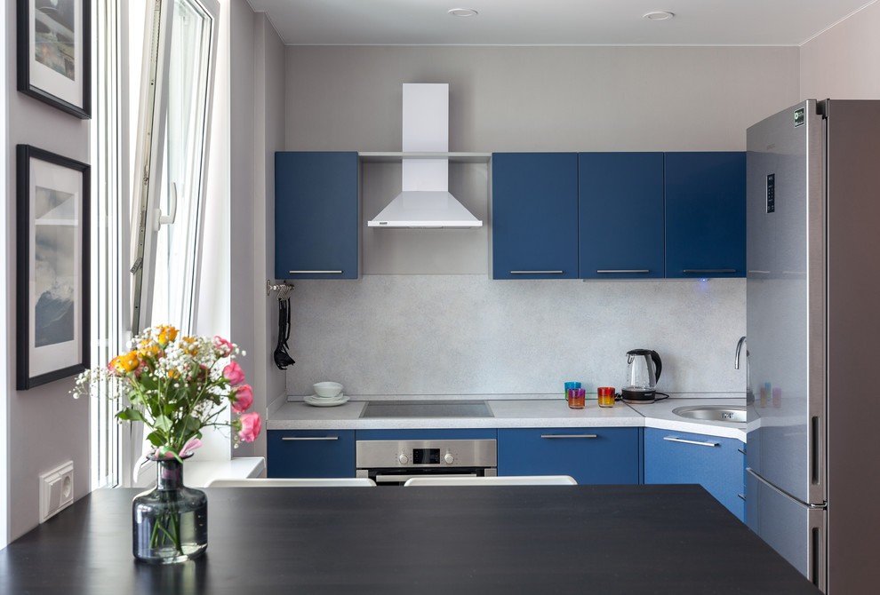 Photo of a small contemporary l-shaped open plan kitchen in Moscow with a drop-in sink, flat-panel cabinets, blue cabinets, white splashback, stainless steel appliances, no island, white benchtop, laminate benchtops, ceramic floors and beige floor.