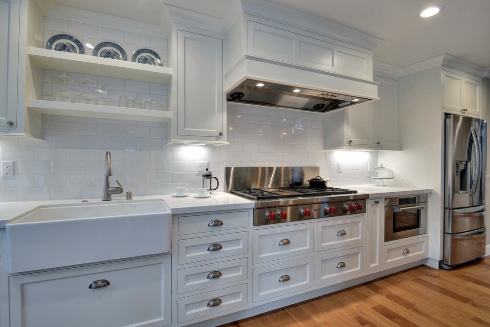 Inspiration for a mid-sized transitional single-wall open plan kitchen in San Francisco with a farmhouse sink, shaker cabinets, grey cabinets, quartz benchtops, white splashback, subway tile splashback, stainless steel appliances, medium hardwood floors and with island.