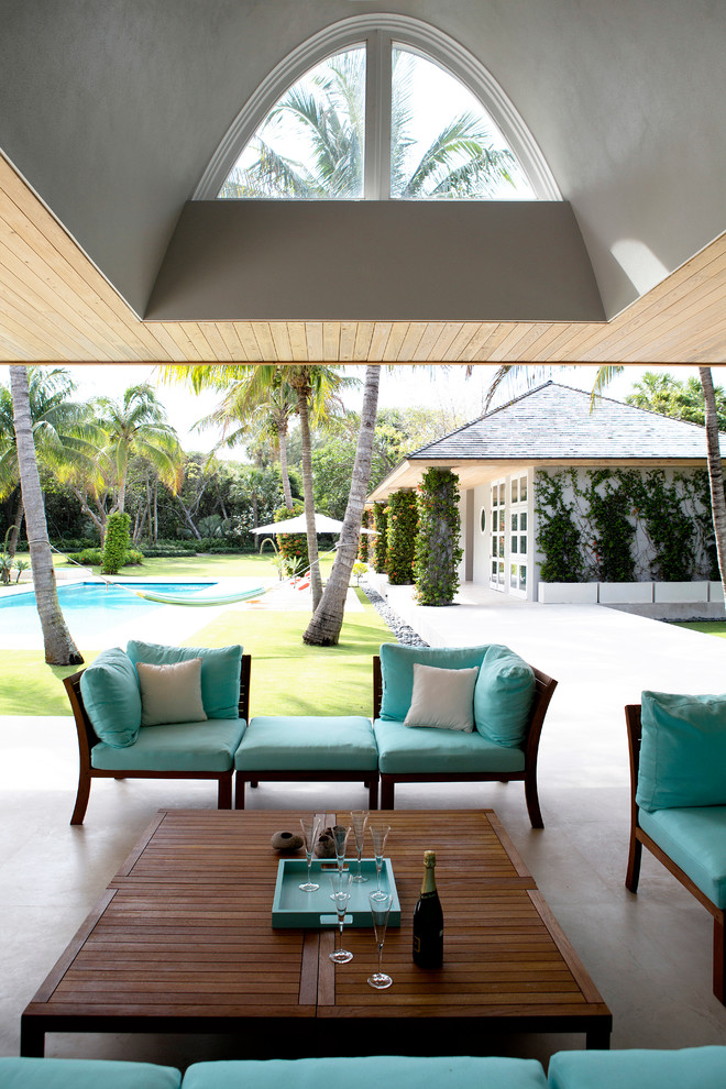 Photo of a mid-sized tropical backyard patio in Miami with a roof extension.