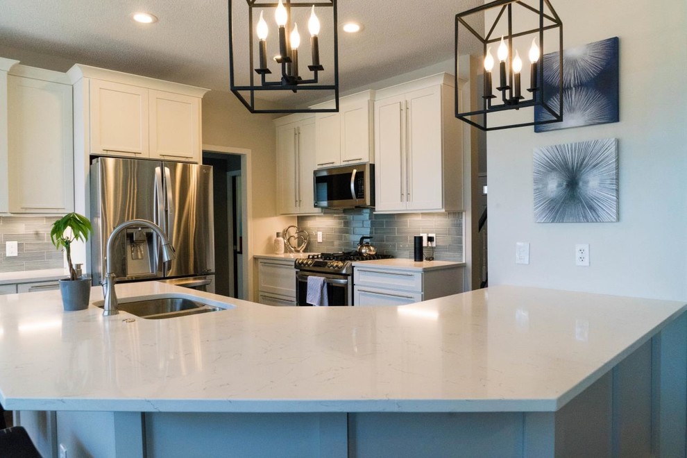 Inspiration for a mid-sized transitional open plan kitchen in Minneapolis with an undermount sink, shaker cabinets, white cabinets, quartzite benchtops, grey splashback, glass tile splashback, stainless steel appliances, dark hardwood floors, a peninsula, brown floor and white benchtop.