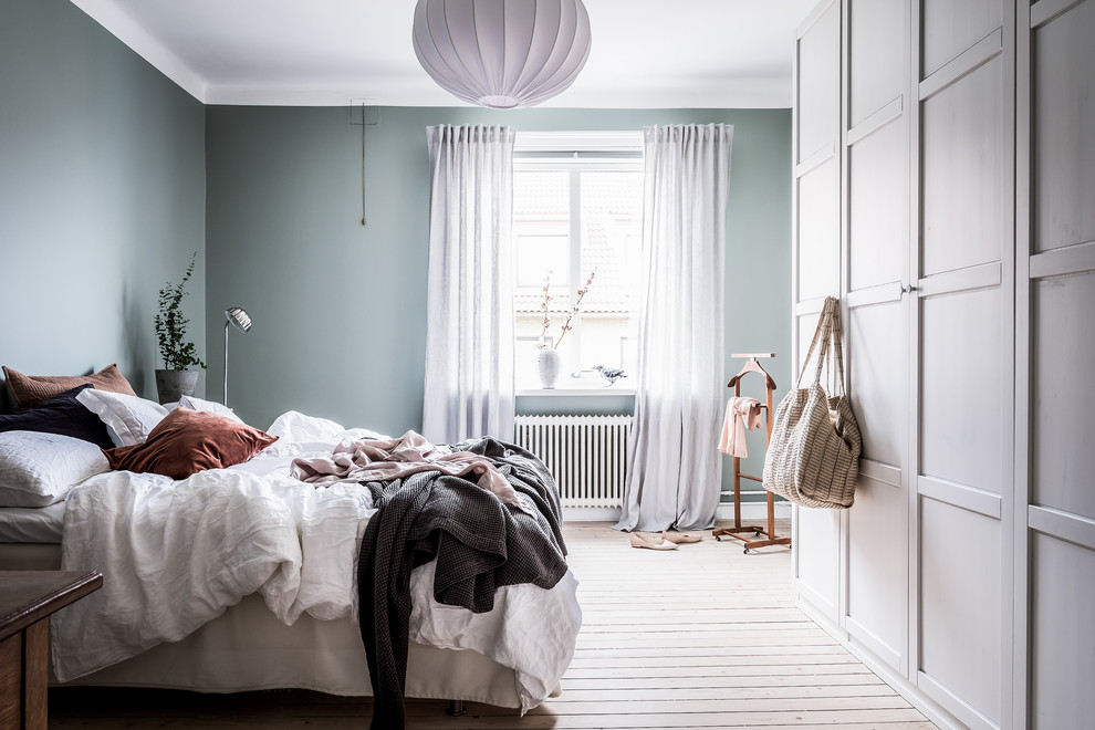 Design ideas for a scandinavian bedroom in Gothenburg with blue walls and light hardwood floors.