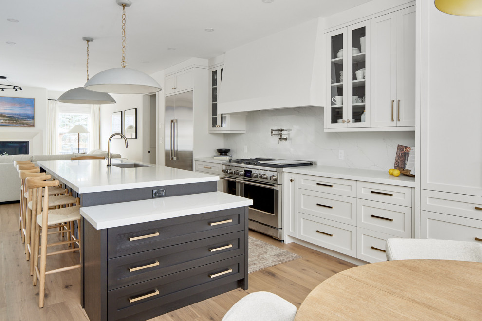 Inspiration for a large transitional single-wall medium tone wood floor and brown floor eat-in kitchen remodel with an undermount sink, shaker cabinets, quartz countertops, white backsplash, quartz backsplash, stainless steel appliances, an island, white countertops and white cabinets