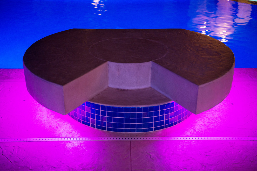 This is an example of a large contemporary courtyard rectangular pool in Cedar Rapids with a hot tub and stamped concrete.