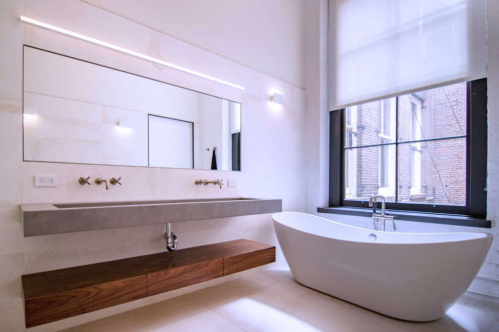 Design ideas for a large industrial master bathroom in New York with flat-panel cabinets, medium wood cabinets, a freestanding tub, a corner shower, a wall-mount toilet, beige tile, porcelain tile, white walls, ceramic floors, a wall-mount sink, concrete benchtops, beige floor, a hinged shower door and grey benchtops.