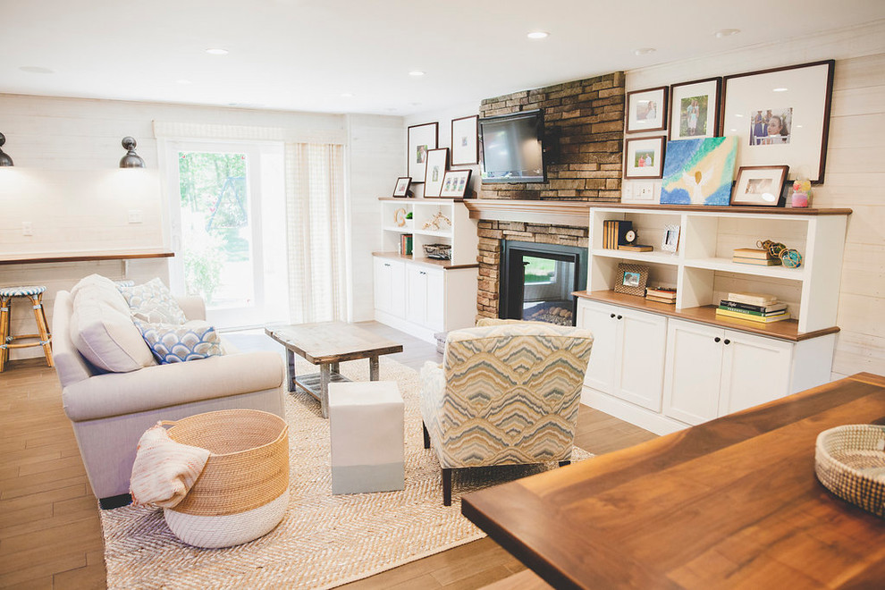 Inspiration for a mid-sized beach style open concept family room in Providence with a home bar, white walls, porcelain floors, a standard fireplace, a stone fireplace surround, a wall-mounted tv and brown floor.