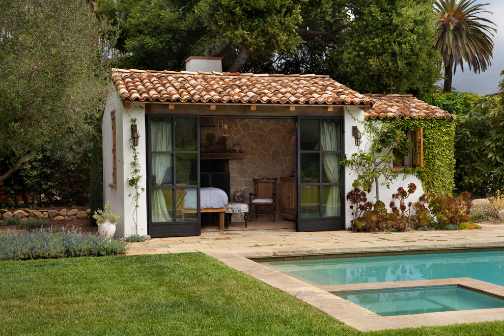 This is an example of a mediterranean rectangular lap pool in Santa Barbara with a pool house and natural stone pavers.