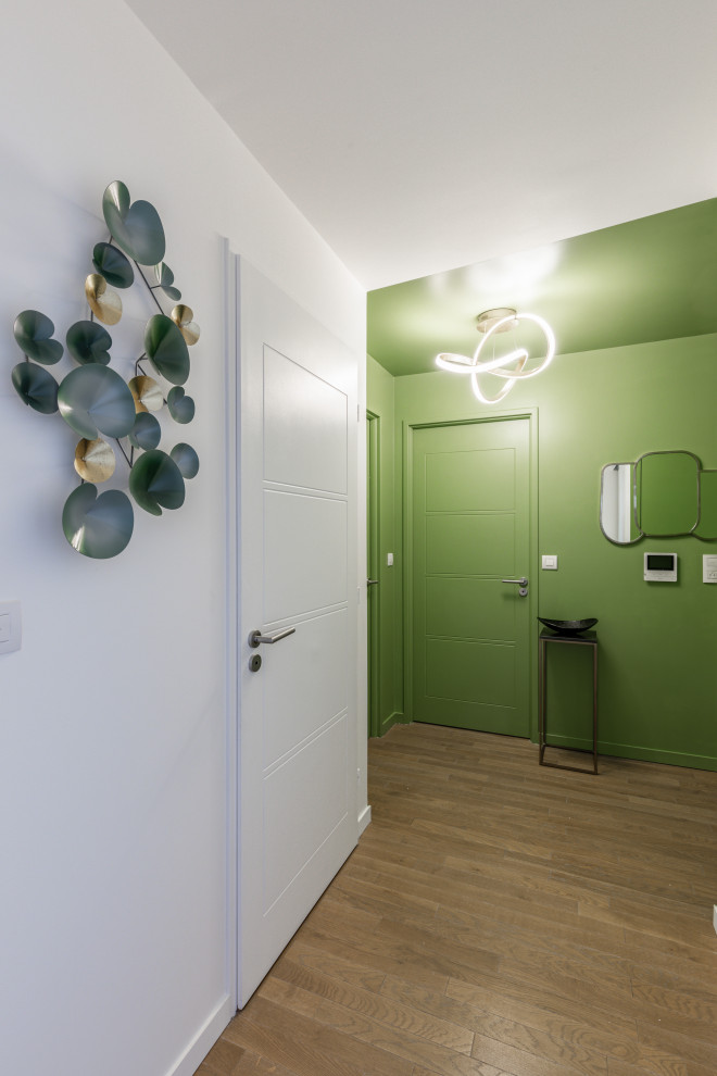 Imagen de entrada ecléctica de tamaño medio con paredes verdes, suelo de madera clara y puerta verde