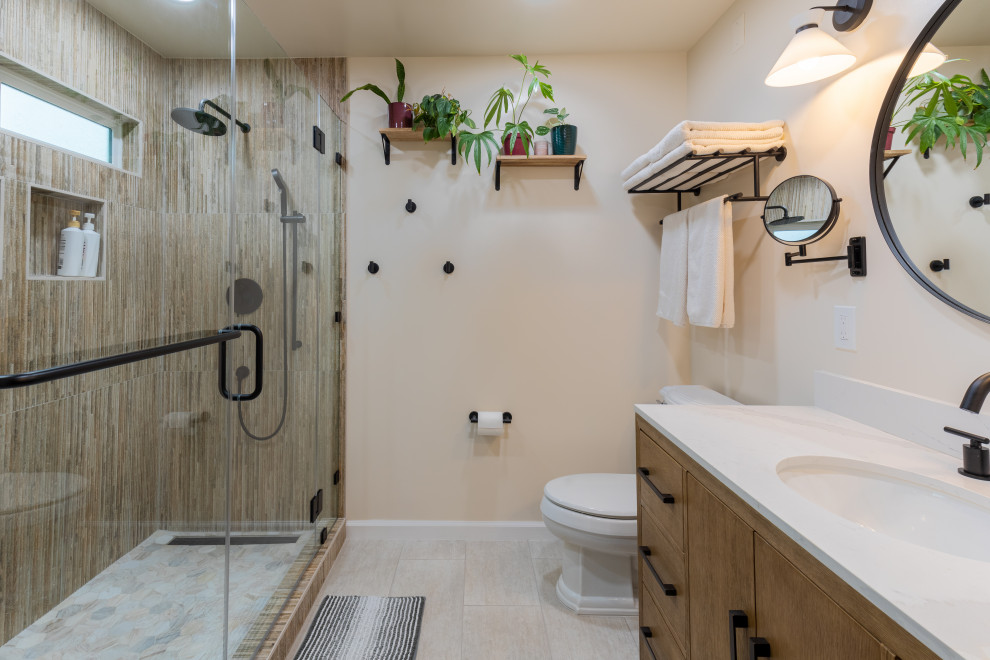 Mid-sized minimalist 3/4 ceramic tile and brown tile ceramic tile, beige floor, double-sink and brick wall corner shower photo in Seattle with flat-panel cabinets, brown cabinets, a two-piece toilet, white walls, an undermount sink, quartz countertops, a hinged shower door, white countertops and a freestanding vanity
