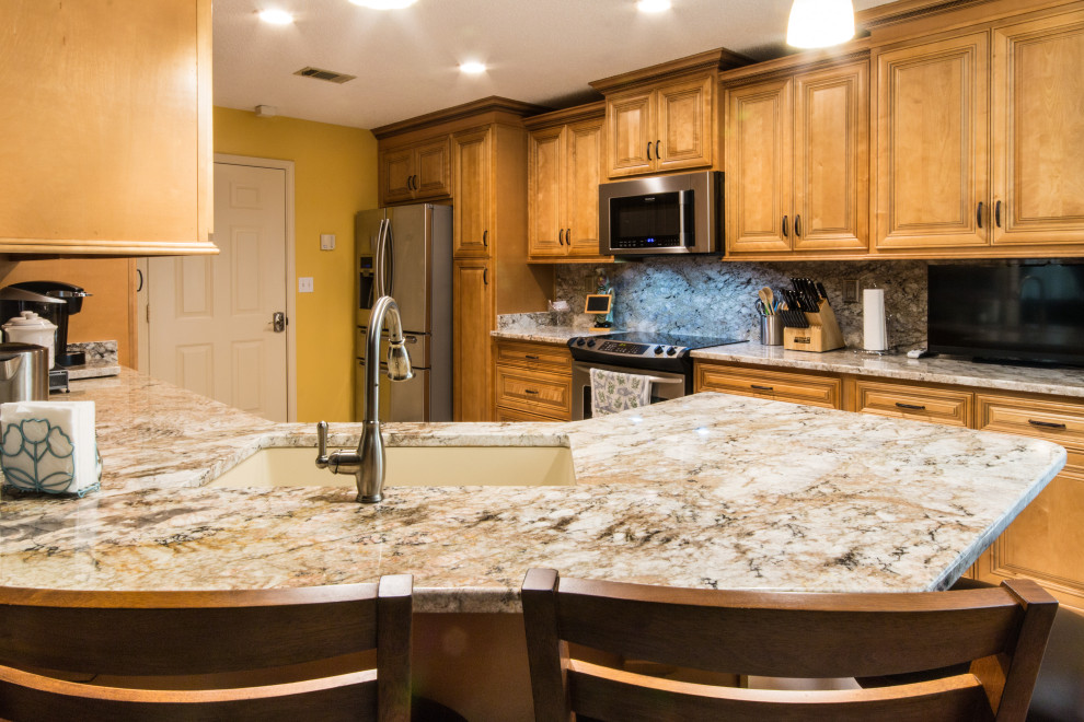 Example of a large u-shaped eat-in kitchen design with an undermount sink, raised-panel cabinets, medium tone wood cabinets, granite countertops, granite backsplash, stainless steel appliances and a peninsula