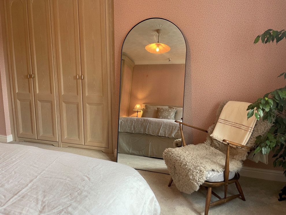 Modelo de dormitorio principal campestre grande con paredes rosas, moqueta, suelo gris y papel pintado