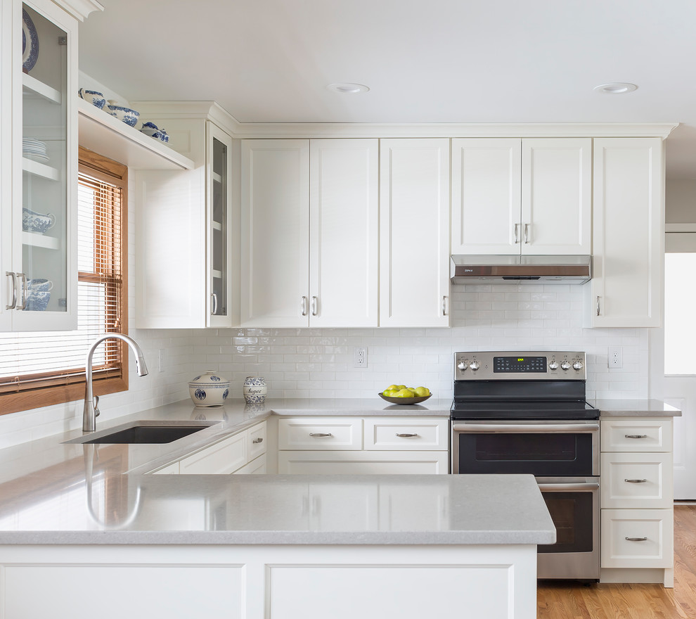 Enclosed kitchen - small transitional u-shaped light wood floor enclosed kitchen idea in Minneapolis with a single-bowl sink, recessed-panel cabinets, white cabinets, quartz countertops, white backsplash, porcelain backsplash, stainless steel appliances and a peninsula