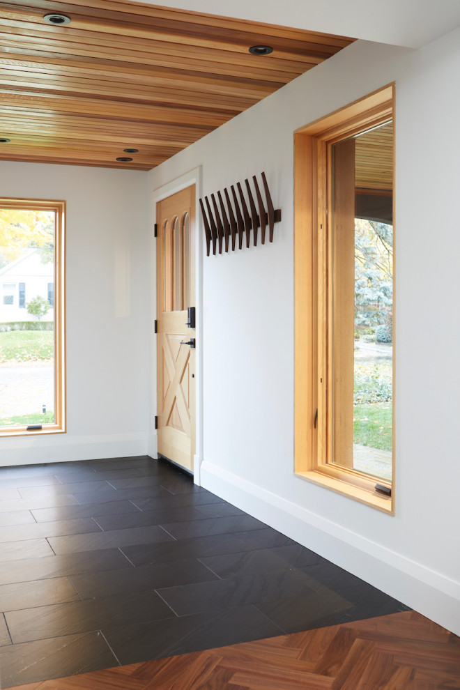 Inspiration pour une entrée avec un vestiaire, un mur blanc, une porte simple, une porte en bois clair, un sol noir et un plafond en bois.