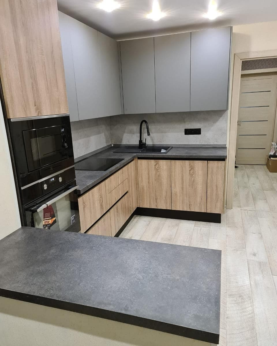 Стильная угловая кухня с деревянными и матовыми фасадами цвета графит