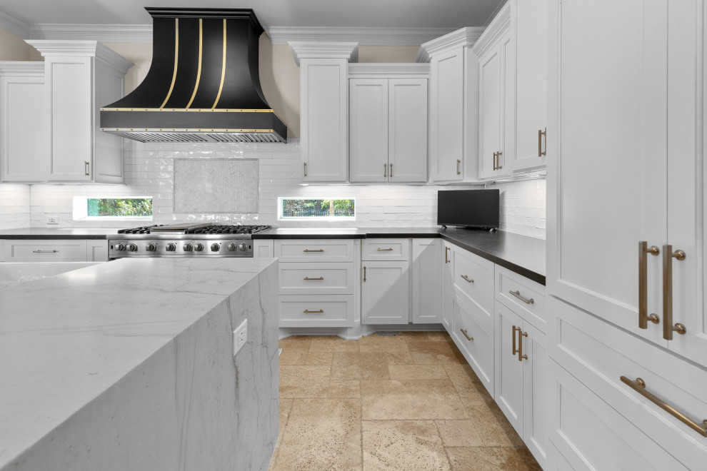Eat-in kitchen - large transitional l-shaped limestone floor and beige floor eat-in kitchen idea in Houston with a farmhouse sink, recessed-panel cabinets, white cabinets, quartzite countertops, white backsplash, limestone backsplash, stainless steel appliances, an island and white countertops
