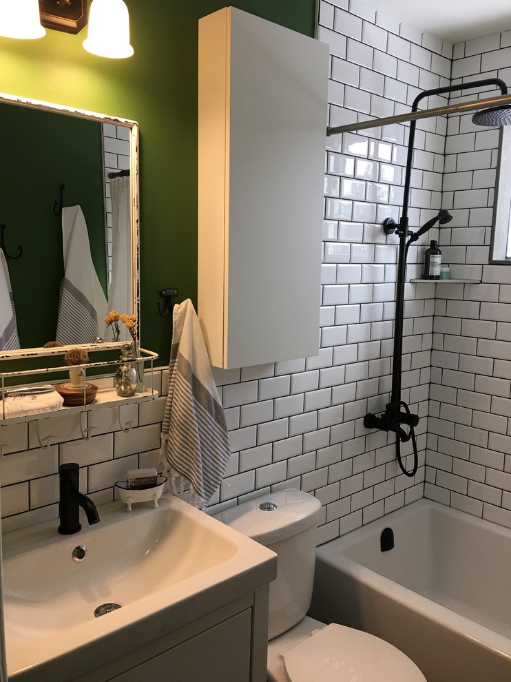 Photo of a small midcentury kids bathroom in Toronto with furniture-like cabinets, white cabinets, an alcove tub, a shower/bathtub combo, a two-piece toilet, white tile, ceramic tile, green walls, ceramic floors, an integrated sink, solid surface benchtops, grey floor, a shower curtain and white benchtops.
