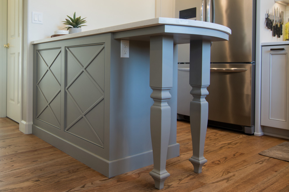Example of a mid-sized transitional l-shaped medium tone wood floor and brown floor kitchen design with an undermount sink, recessed-panel cabinets, gray cabinets, quartz countertops, white backsplash, ceramic backsplash, stainless steel appliances, a peninsula and white countertops