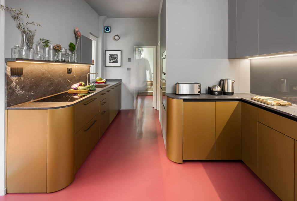 Design ideas for a medium sized retro open plan kitchen in Other with a single-bowl sink, flat-panel cabinets, grey cabinets, granite worktops, grey splashback, glass sheet splashback, stainless steel appliances, concrete flooring, red floors and black worktops.