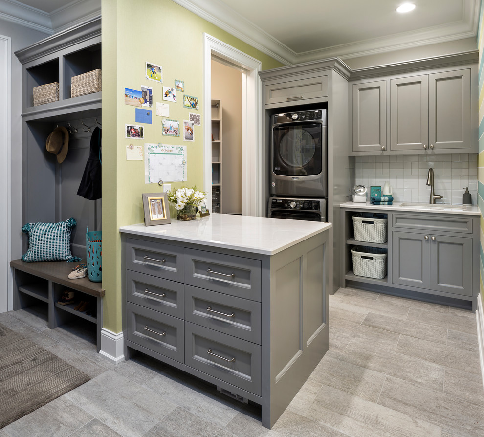This is an example of a large traditional galley utility room in Minneapolis with an undermount sink, recessed-panel cabinets, grey cabinets, marble benchtops, porcelain floors, a stacked washer and dryer, beige floor and green walls.