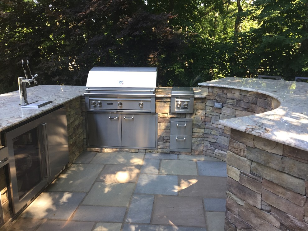 This is an example of a traditional backyard patio in New York with an outdoor kitchen.