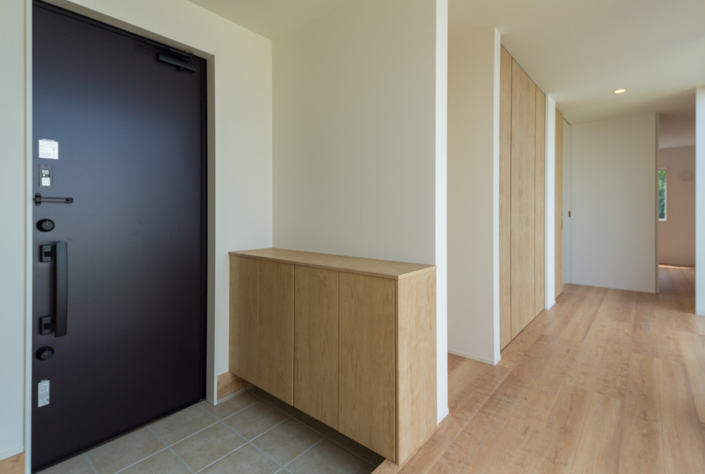 Стильный дизайн: узкая прихожая среднего размера в скандинавском стиле с белыми стенами, светлым паркетным полом, одностворчатой входной дверью и черной входной дверью - последний тренд