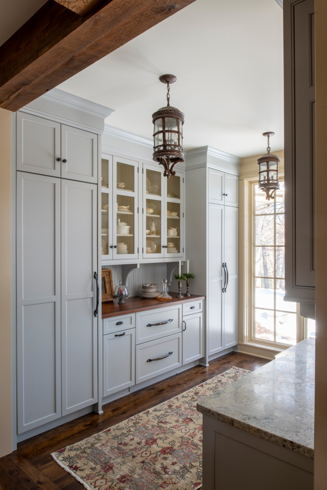 Large traditional l-shaped kitchen pantry in Minneapolis with a farmhouse sink, recessed-panel cabinets, blue cabinets, granite benchtops, beige splashback, ceramic splashback, stainless steel appliances, medium hardwood floors, with island, brown floor, beige benchtop and exposed beam.