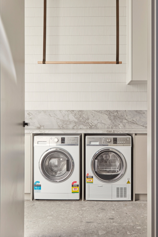 Design ideas for a large contemporary galley dedicated laundry room in Melbourne with a drop-in sink, flat-panel cabinets, white cabinets, marble benchtops, white splashback, ceramic splashback, white walls, ceramic floors, a side-by-side washer and dryer, grey floor and white benchtop.