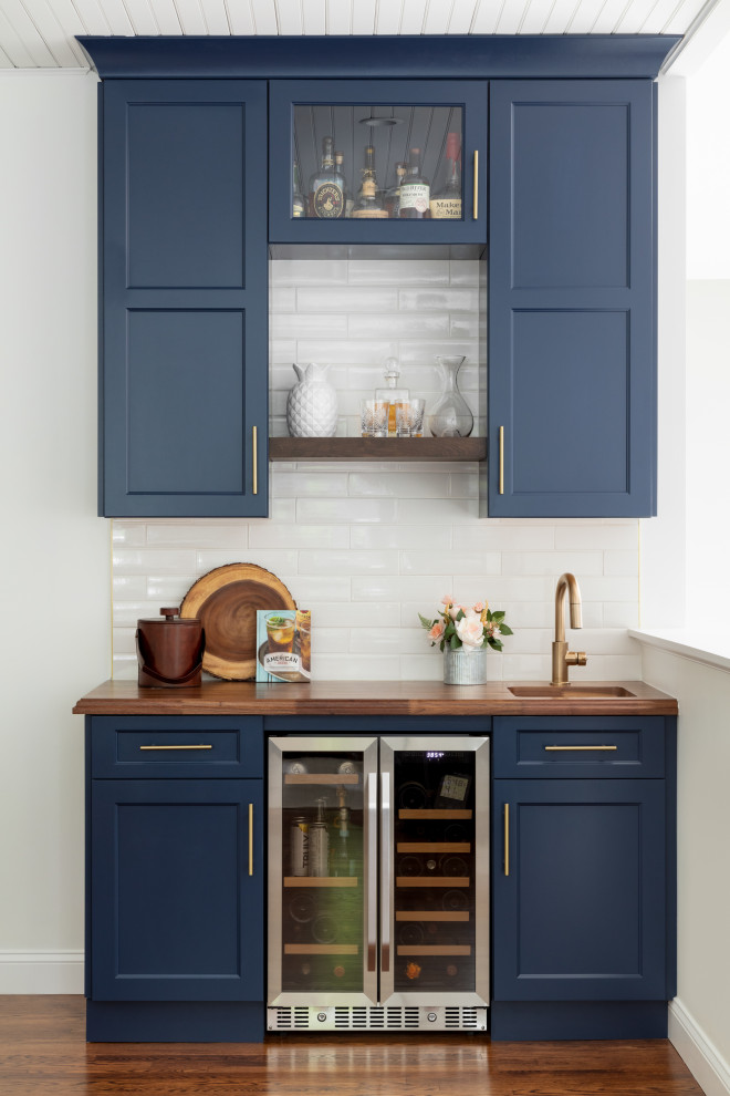 Inspiration for a transitional single-wall wet bar in Boston with an undermount sink, shaker cabinets, blue cabinets, wood benchtops, white splashback, mosaic tile splashback, medium hardwood floors, brown floor and brown benchtop.