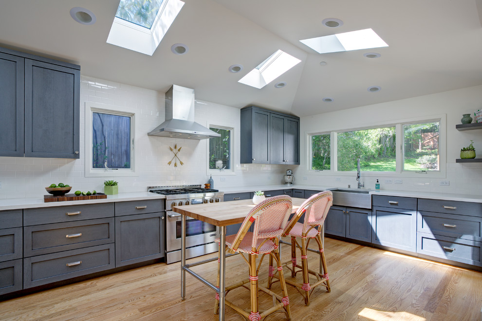 Arts and crafts eat-in kitchen in San Francisco with a farmhouse sink, shaker cabinets, grey cabinets, quartz benchtops, white splashback, subway tile splashback, stainless steel appliances, light hardwood floors and with island.