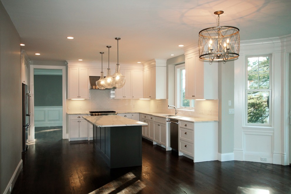 Mid-sized transitional u-shaped dark wood floor and brown floor eat-in kitchen photo in Boston with an undermount sink, shaker cabinets, white cabinets, marble countertops, white backsplash, porcelain backsplash, stainless steel appliances and an island