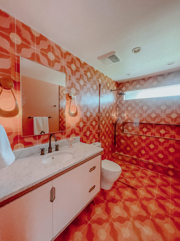Foto på ett stort 60 tals badrum med dusch, med släta luckor, lila skåp, en kantlös dusch, orange kakel, cementkakel, marmorbänkskiva, rosa golv och med dusch som är öppen