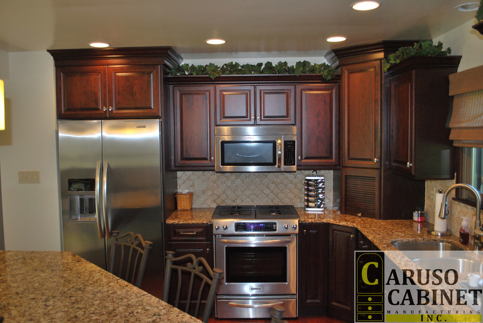 Small elegant l-shaped medium tone wood floor eat-in kitchen photo with a double-bowl sink, raised-panel cabinets, dark wood cabinets, quartzite countertops, beige backsplash, ceramic backsplash, stainless steel appliances and an island