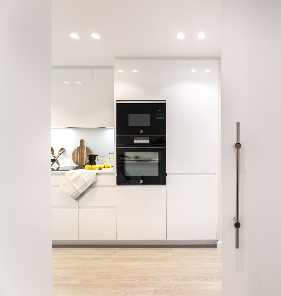 Inspiration for a medium sized modern l-shaped enclosed kitchen in Barcelona with a submerged sink, white cabinets, engineered stone countertops, white splashback, engineered quartz splashback, black appliances, ceramic flooring, no island, beige floors and white worktops.