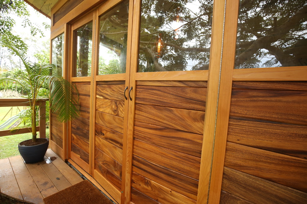 This is an example of a small tropical front door in Hawaii with brown walls, a double front door and a medium wood front door.