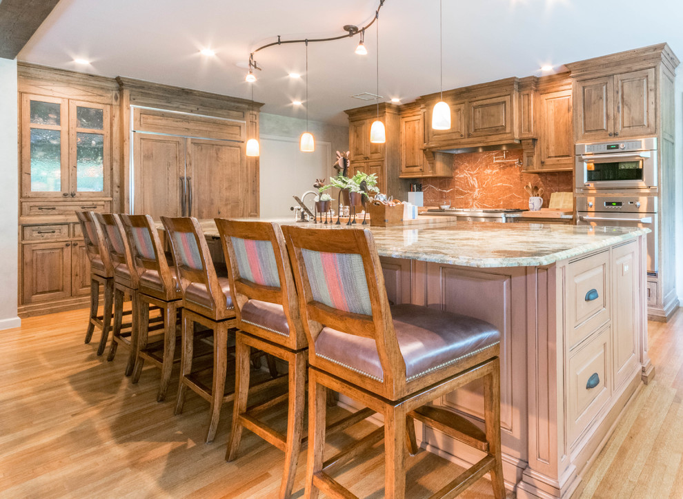 Example of a large mountain style u-shaped eat-in kitchen design with distressed cabinets, granite countertops, stone slab backsplash, stainless steel appliances and an island