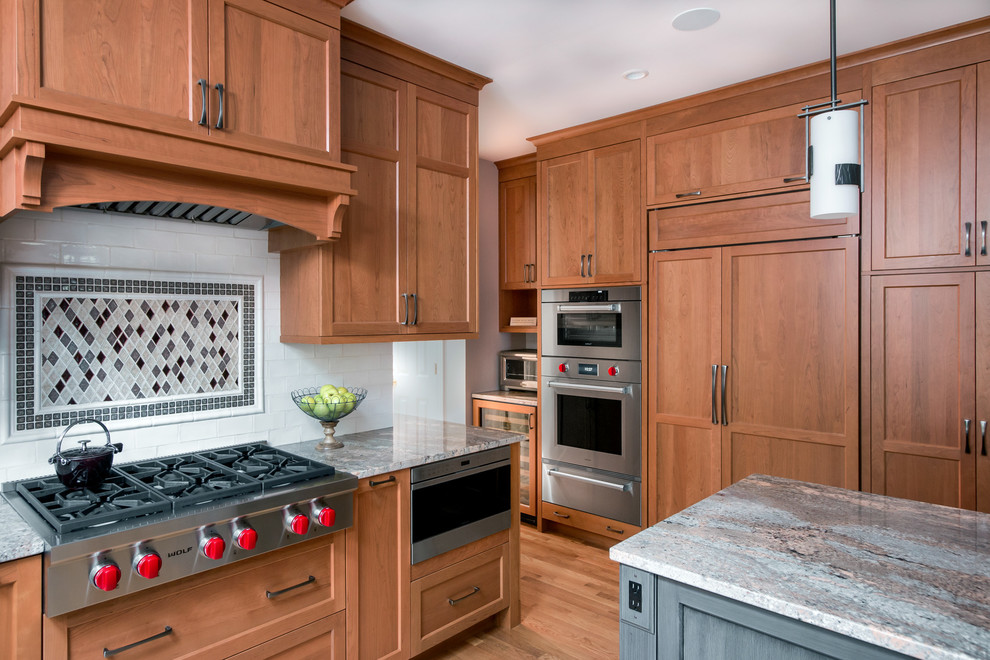 This is an example of a mid-sized transitional u-shaped eat-in kitchen in Boston with an undermount sink, shaker cabinets, light wood cabinets, granite benchtops, white splashback, subway tile splashback, stainless steel appliances, dark hardwood floors and with island.