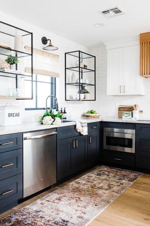 Modern kitchen with navy Shaker base cabinets featuring deep drawers and brass pulls, open metal wall shelves, white brick backsplash, and stainless appliances—showing optimized base-cabinet storage