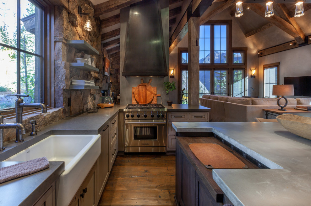 Inspiration for a mid-sized country u-shaped open plan kitchen in Denver with a farmhouse sink, shaker cabinets, distressed cabinets, concrete benchtops, brown splashback, stone tile splashback, panelled appliances, dark hardwood floors, with island, brown floor, grey benchtop and exposed beam.
