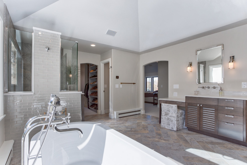 Photo of an expansive beach style master bathroom in Denver with louvered cabinets, medium wood cabinets, a freestanding tub, a corner shower, a two-piece toilet, multi-coloured tile, glass tile, beige walls, ceramic floors, an undermount sink and engineered quartz benchtops.