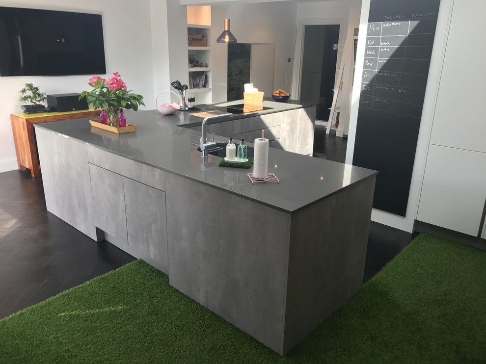 Design ideas for a large contemporary l-shaped eat-in kitchen in Kent with an undermount sink, flat-panel cabinets, white cabinets, quartzite benchtops, multi-coloured splashback, cement tile splashback, black appliances, vinyl floors, with island, black floor and grey benchtop.