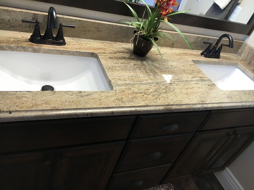 Mid-sized transitional master beige tile and porcelain tile porcelain tile drop-in bathtub photo with raised-panel cabinets, dark wood cabinets, a two-piece toilet, beige walls, an undermount sink and granite countertops
