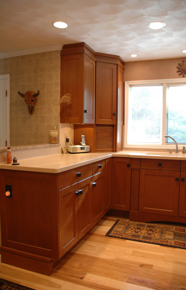 This is an example of an arts and crafts u-shaped eat-in kitchen in Indianapolis with an undermount sink, shaker cabinets, medium wood cabinets, granite benchtops, panelled appliances and light hardwood floors.