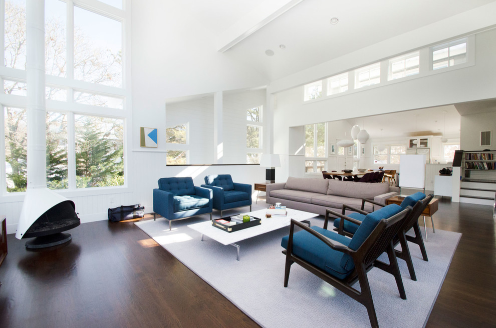 Contemporary open concept living room in New York with white walls and dark hardwood floors.