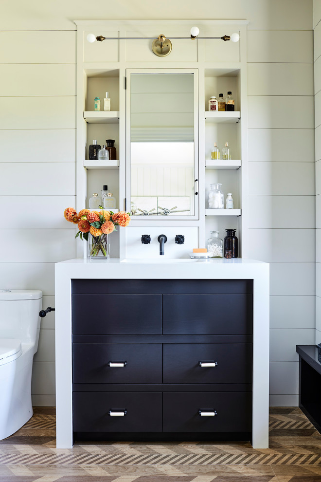 Rustik inredning av ett vit vitt badrum för barn, med släta luckor, svarta skåp, en toalettstol med hel cisternkåpa, vita väggar och brunt golv